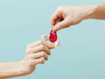 people-holding-red-condom-blue-background