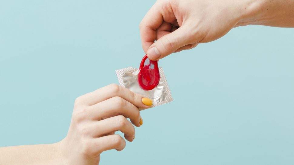 people-holding-red-condom-blue-background