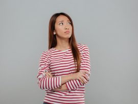 portrait-depressed-asian-woman-standing-with-arms-folded_171337-13564