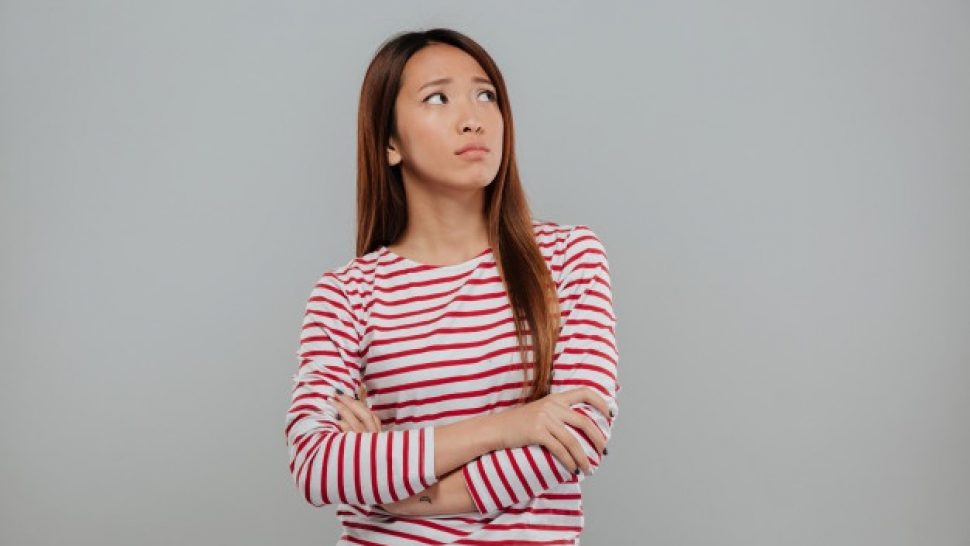 portrait-depressed-asian-woman-standing-with-arms-folded_171337-13564