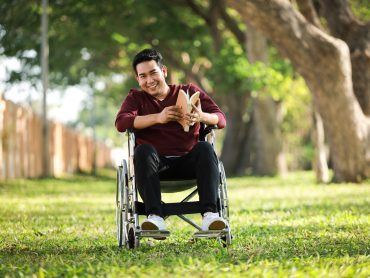 Asian Young Man sitting on the wheelchair in the park hospital