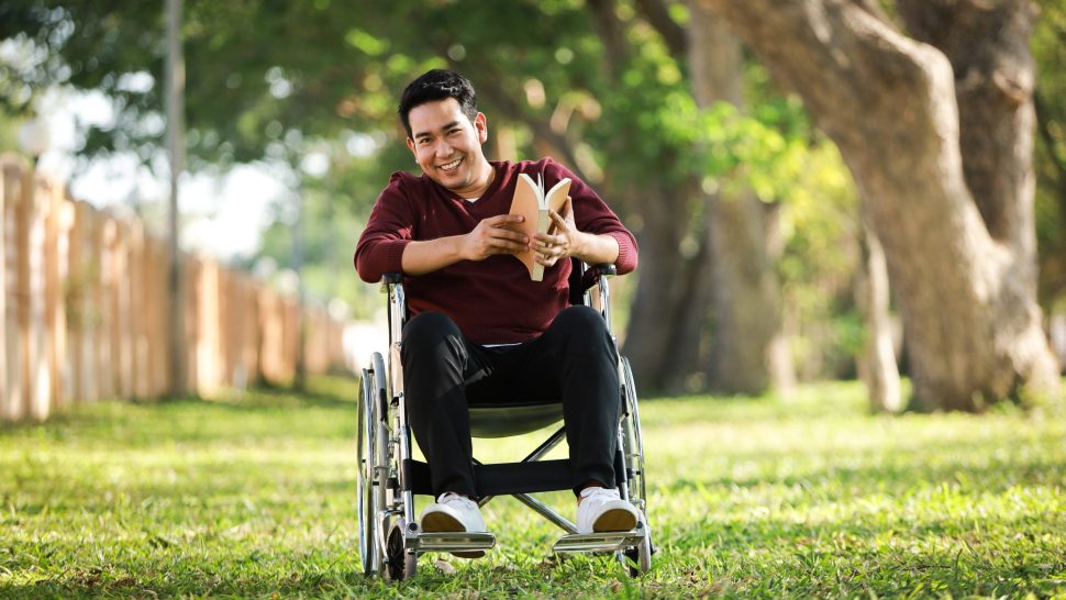 Asian Young Man sitting on the wheelchair in the park hospital