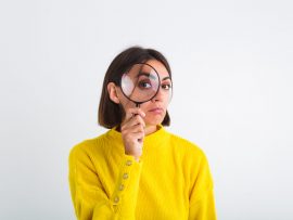 Pretty woman in yellow sweater on white background held magnifier happy positive playful