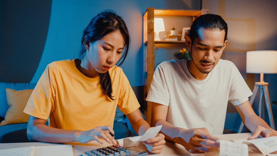 Stress asia couple man and woman use calculator for calculate family budget, debts, expenses during financial economic crisis at home at night. Marriage money trouble, Family budget plan concept.