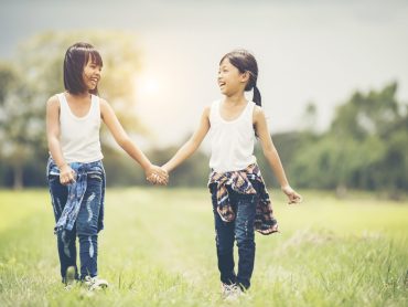 Two little girls hand holding together having fun in the park Two little girls hand holding together having fun in the park
