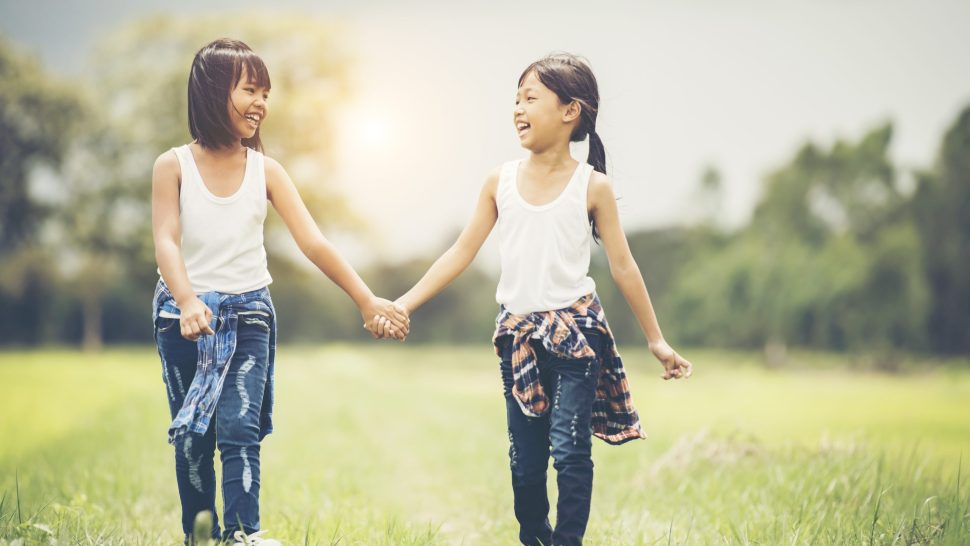 Two little girls hand holding together having fun in the park